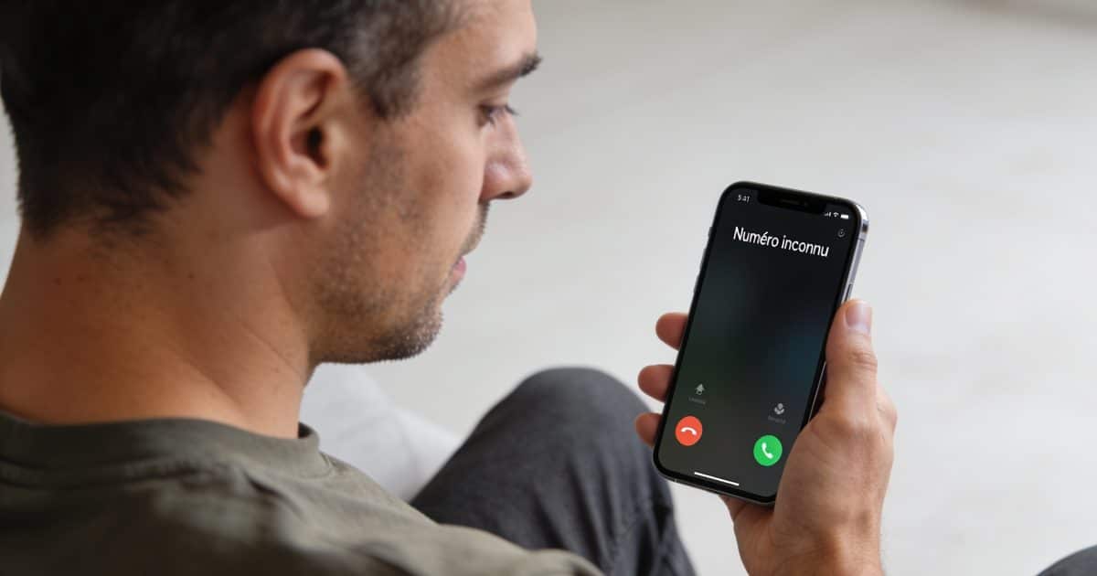 Homme regarde ecran de smartphone affichant numero inconnu