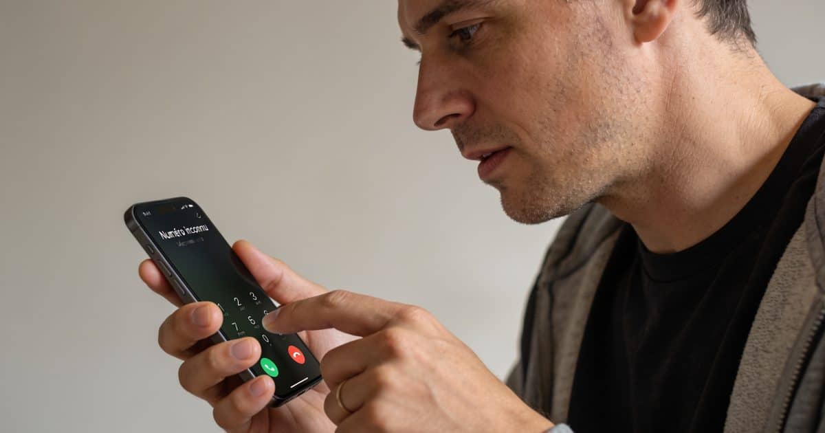 Homme regarde ecran smartphone affichant numero inconnu