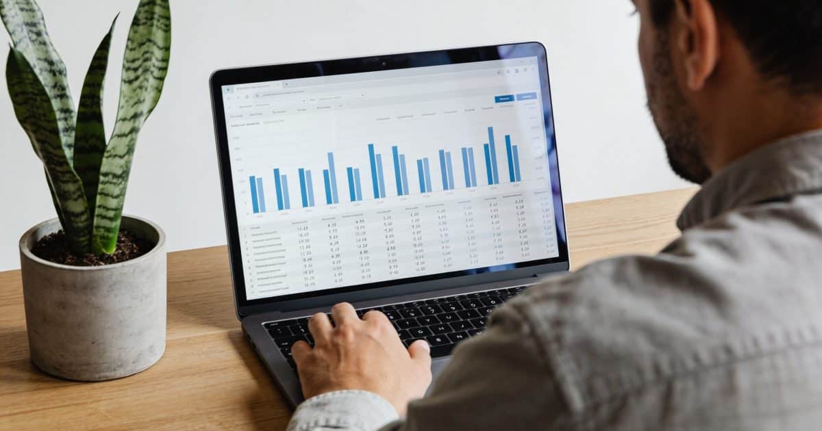 Proprietaire assis devant ordinateur affichant tableau financier