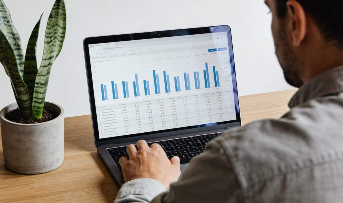 Proprietaire assis devant ordinateur affichant tableau financier