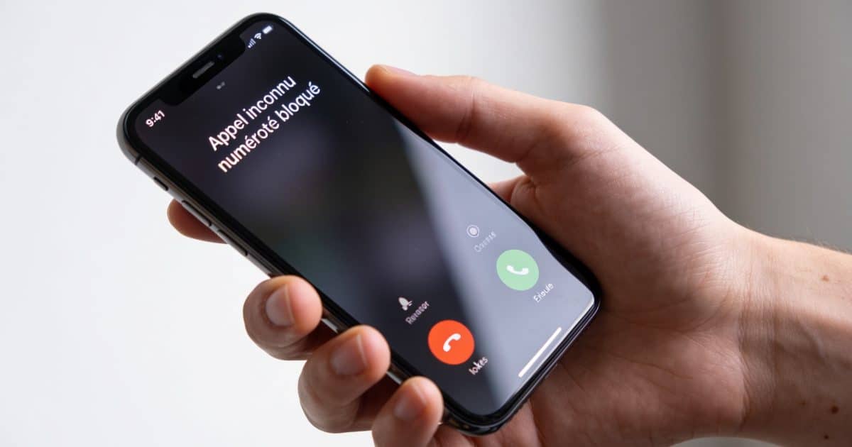 Smartphone en main affichant appel inconnu numerote bloque