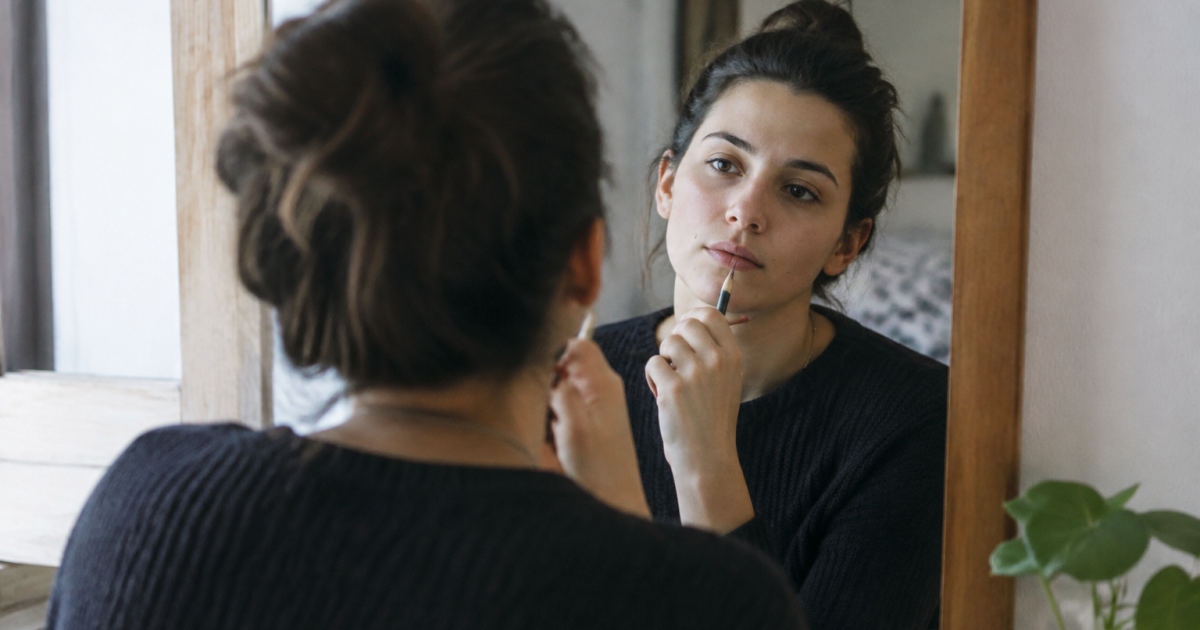 Jeune femme assise devant un miroir tenant un crayon