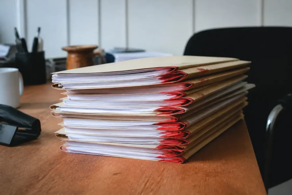 Pile de dossiers papier avec intercalaires rouges sur bureau